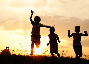 Silhouette, group of happy children playing on meadow, sunset, summertime