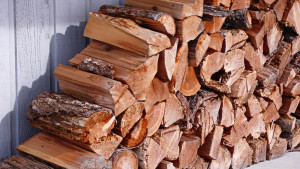 A pile of split firewood neatly stacked and organized in front of a shed.